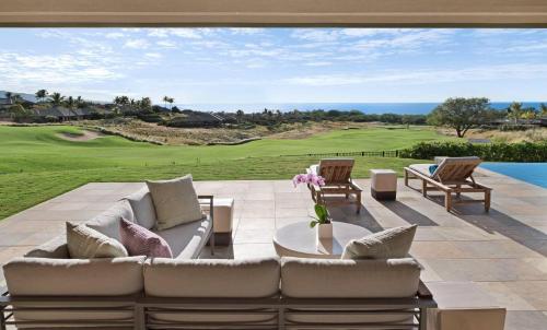 a patio with a couch and a view of a golf course at Hale Keanu in Hapuna Beach