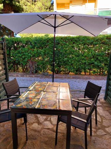 une table avec un parasol et deux chaises dans l'établissement Prélude Beach, à Bormes-les-Mimosas
