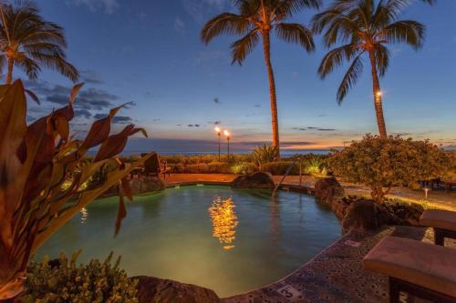 a swimming pool with palm trees in a resort at Hale Pikake in Hapuna Beach