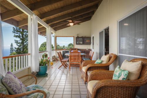 a screened in porch with wicker chairs and a table at Hale Mauka in Captain Cook