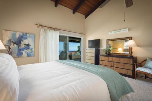 a bedroom with a large white bed and a television at Hale Mauka in Captain Cook
