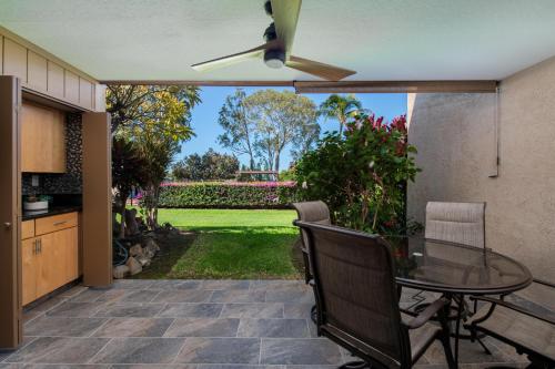 a patio with a table and chairs and a garden at Hale Polū in Waikoloa Village