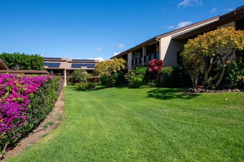a building with a yard with flowers at Hale Polū in Waikoloa Village