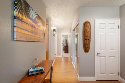 a hallway with a wooden table and a white door at Hale Polū in Waikoloa Village