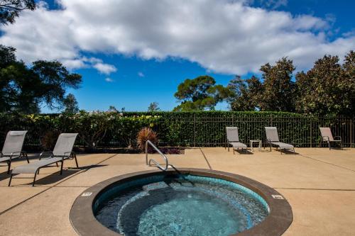 a swimming pool with chairs and a hot tub at Hale Polū in Waikoloa Village