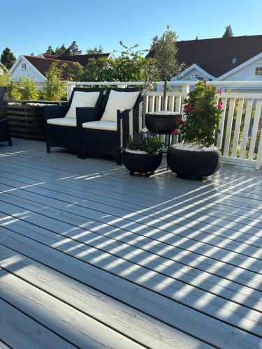 a wooden deck with two chairs and plants on it at Flott enebolig nær sjøen, Hvaler og Fredrikstad in Fredrikstad
