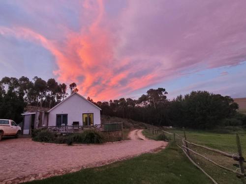 a house on a dirt road with a cloudy sky at Kleinwatervalplaas Farm Stay Accomodation in Caledon