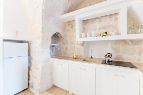 a kitchen with white cabinets and a stone wall at Casa Zio Piero in Ostuni