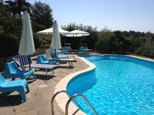 a swimming pool with blue chairs and umbrellas at Podere La Branda in Vetralla