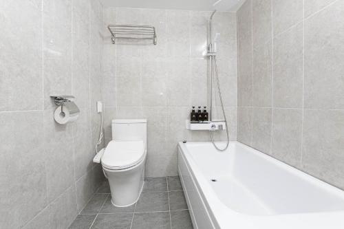 a white bathroom with a toilet and a bath tub at Hotel Centro Stay in Incheon