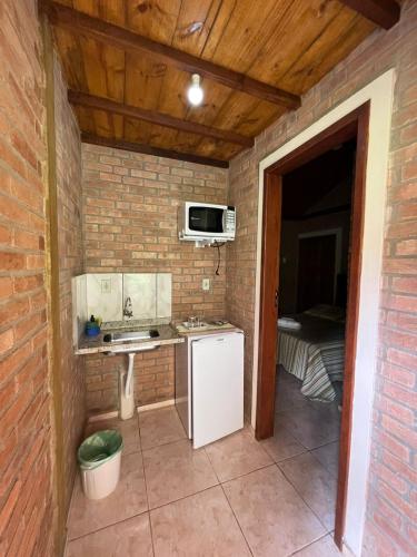 a small kitchen with a refrigerator and a microwave at CHALÉ NATIVO R Júlio Miranda nº 06 in Conceição da Ibitipoca