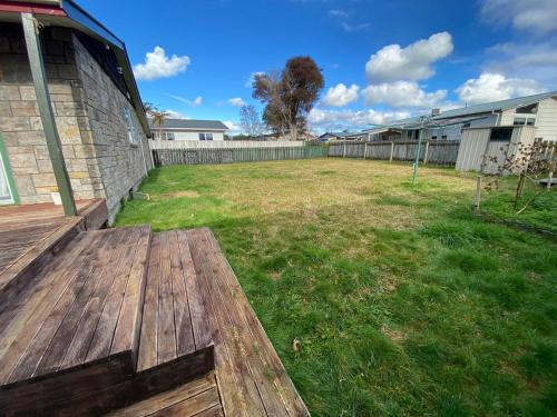 a backyard with a wooden deck and a yard at 3 Bedroom House, 95 Aquirus Drive, Rotorua in Rotorua