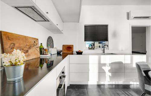 a kitchen with white cabinets and a vase of flowers at 2 Bedroom Amazing Home In Otterup in Otterup