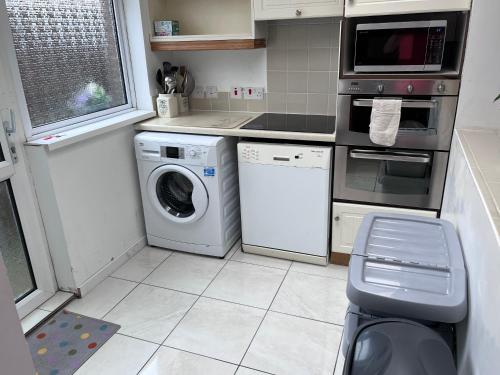 a kitchen with a washing machine and a microwave at Spacious 5 double bed bedroom bungalow near Belfast in Lisburn
