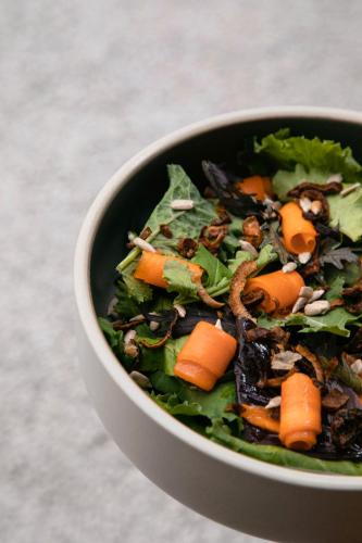 a bowl of salad with carrots and greens at DOWNTOWN DESIGN LOFT in Cusco