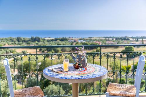 a table with a glass of orange juice on top of a balcony at Liogerma Art Deco Villa - 5 min drive to Lassi in Sarlata