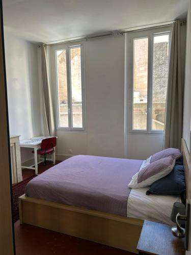 a bedroom with a bed and two windows at Historique vieux port in Marseille