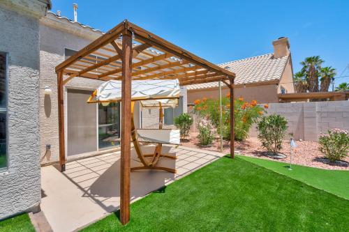 a wooden pergola in a backyard with a lawn at 8BR 5BA SuperHero Retreat-King Beds, BBQ, Hammock, Firepit, MiniGolf, WorkSpace in Las Vegas