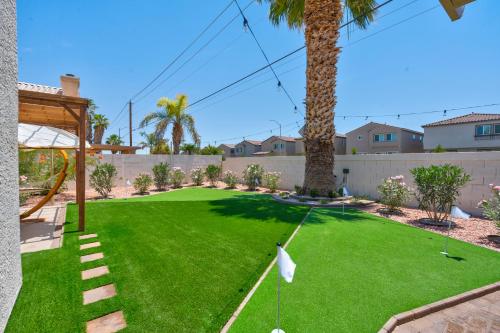 a yard with a putting green and palm trees at 8BR 5BA SuperHero Retreat-King Beds, BBQ, Hammock, Firepit, MiniGolf, WorkSpace in Las Vegas