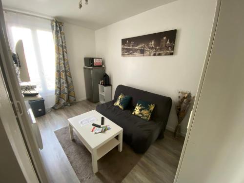 un salon avec un canapé noir et une table dans l'établissement Studette 13m2, à Bagnolet