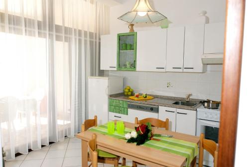 a kitchen with white cabinets and a table with a green tablecloth at Apartments Villa Ada in Vinkuran
