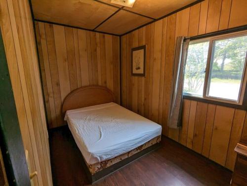 a small bed in a room with a window at Tiny Wood Cottage 05 in Wasaga Beach