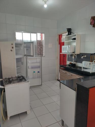 eine Küche mit weißen Geräten und roten Schränken in der Unterkunft Casa de praia para temporada in Paulista
