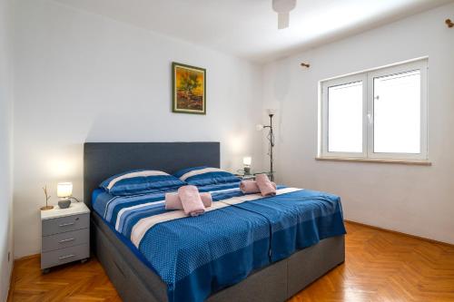 a bedroom with a bed with blue sheets and a window at Pool apartman Maja in Šibenik