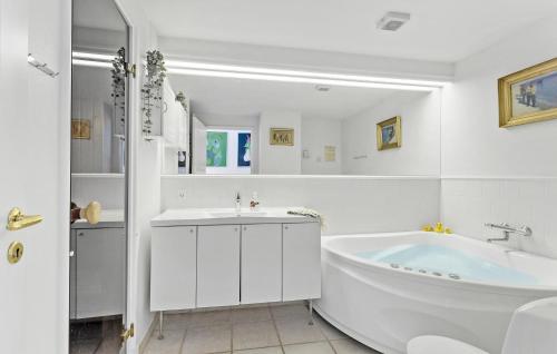 a white bathroom with a tub and a sink at Cozy Apartment In Bagenkop With Sauna in Bagenkop