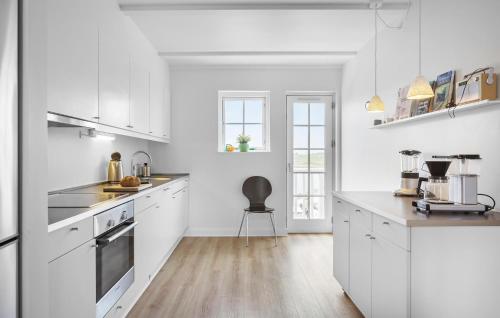 a kitchen with white cabinets and a chair in it at Pet Friendly Apartment In Bagenkop in Bagenkop