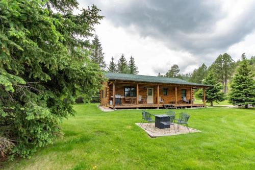 a log cabin with a picnic table and chairs in the yard at Tenderfoot Creek Cabin in Custer