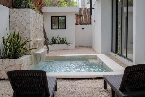 Una piscina en medio de un patio con dos sillas. en Jungle Retreat Luxury Villa with Pool inTulum, en Tulum