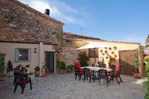 Un patio con una mesa y sillas y una sombrilla. en Casa Calvo SXVI, en Santa Eulalia la Mayor