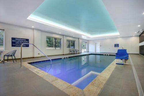 a swimming pool with a blue chair and a sign at Tru By Hilton Wake Forest Raleigh North in Wake Forest