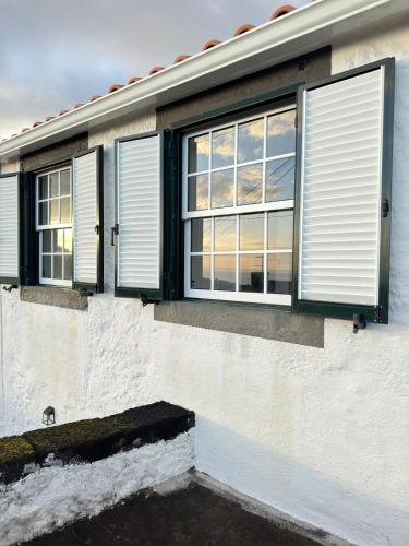 a white house with windows and green shutters at Vista Pico House in Madalena