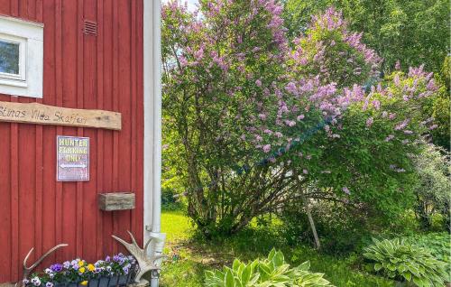 SävsjöにあるAmazing Home In Sävsjö With Wifiの赤い建物と、その隣に花が咲いた茂み