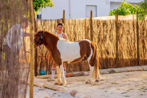 a young girl standing next to a brown and white horse at La Quinta da Liberdade - Ferme de charme en Algarve in Pechão