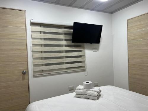 a room with a bed with a television and towels at Hotel Orduz Centro Histórico de Cali in Cali