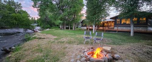 two chairs sitting around a fire in front of a house at Beautiful Craftsman Home with Riverfront Views! in Lander