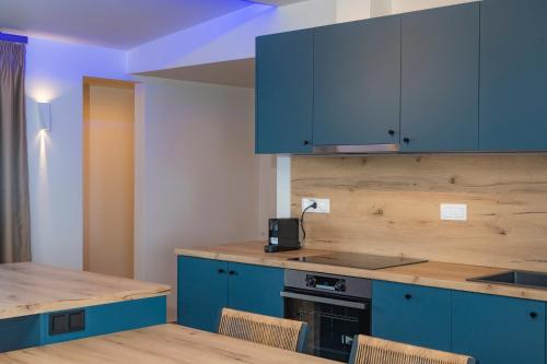a kitchen with blue cabinets and a table and chairs at POSEIDON Seaview Presidential in Paralia Katerinis
