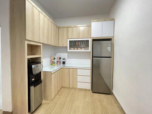a kitchen with wooden cabinets and a stainless steel refrigerator at Penuin Guest House Gaia 09 Batam in Nagoya