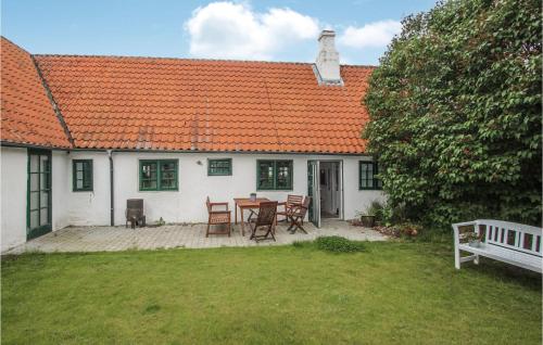 a white house with an orange roof with a table and chairs at Cozy Apartment In Samsø With Wifi in Nordby