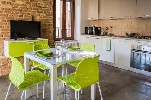 une cuisine avec une table blanche et des chaises vertes dans l'établissement La Rocchetta, à Ripatransone