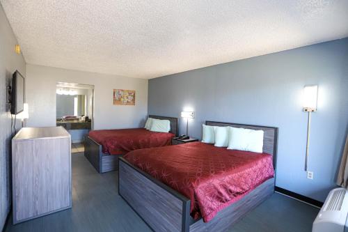 a hotel room with two beds with red sheets at Express Inn in Durant