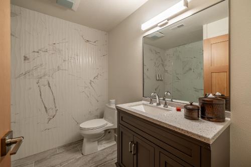 a bathroom with a sink and a toilet and a mirror at Bavarian Lodge Suites in Leavenworth