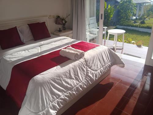 a bedroom with a bed with a red and white comforter at Gill Lake Batur in Kubupenlokan