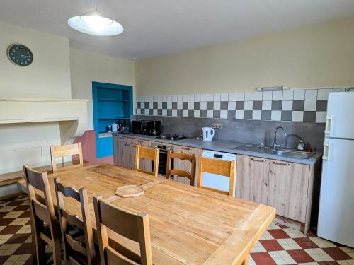 une cuisine avec une table en bois avec des chaises et un réfrigérateur dans l'établissement Gîte accueillant 10 pers avec terrasse, proche nature, idéal pour famille et PMR à Mécrin - FR-1-585-12, à Mécrin