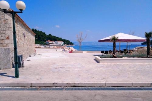 a patio with a beach and an umbrella and the ocean at Apartments with WiFi Pitve, Hvar - 22114 in Jelsa