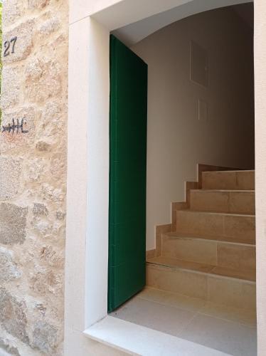 a green door on the side of a building with stairs at Apartments with WiFi Pitve, Hvar - 22114 in Jelsa