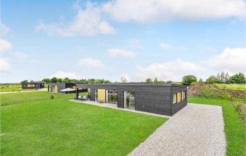a modern house with a black facade on a green field at Gorgeous Home In Løgstrup With Kitchen in Løgstrup